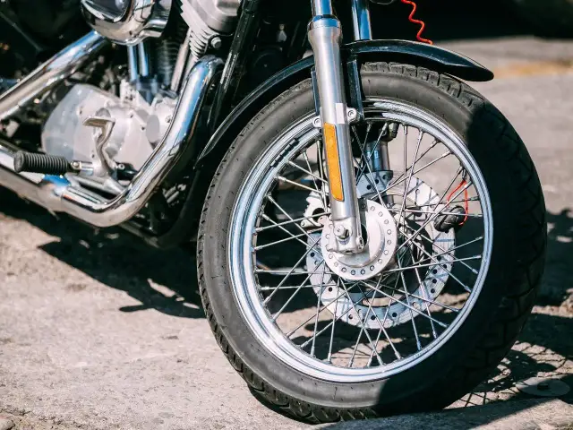 Zbliżenie na przednie koło motocykla z widocznym silnikiem i chromowanymi elementami.