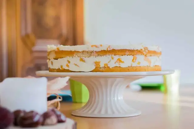 Ein leckerer no bake kuchen mit Sahne und Fruchtstücken auf einem Tortenständer.
