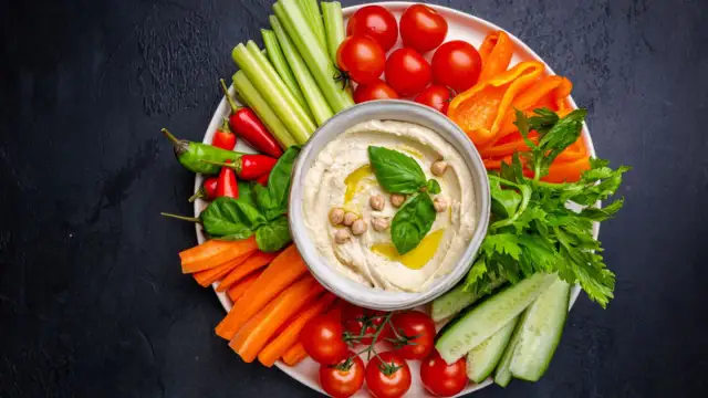 Bunte Gemüsesticks mit Hummus – ein köstliches veganes Fingerfood. Karotten, Gurken, Paprika, Sellerie, Tomaten und Chili laden zum Dippen ein.