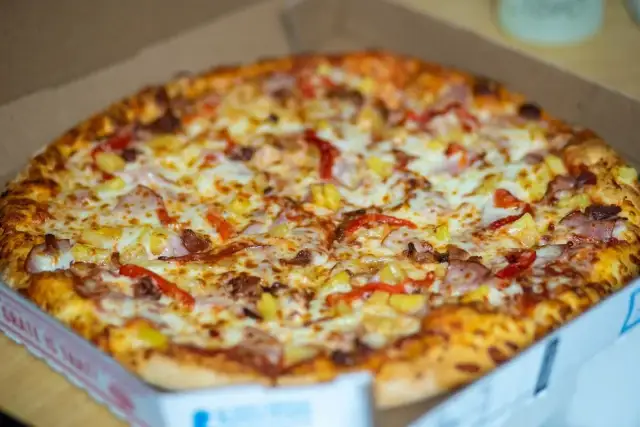 Pyszna pizza hawajska w pudełku, idealna do szybkiego odgrzania w mikrofali.