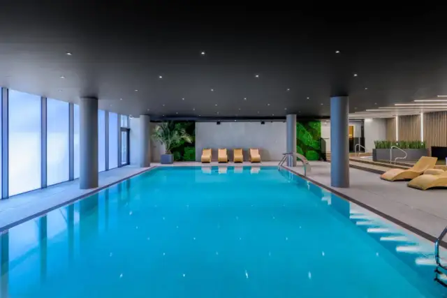 Basen w AC Hotels Krakow. Relaks przy basenie z widokiem na zielone ściany i nowoczesne leżaki.