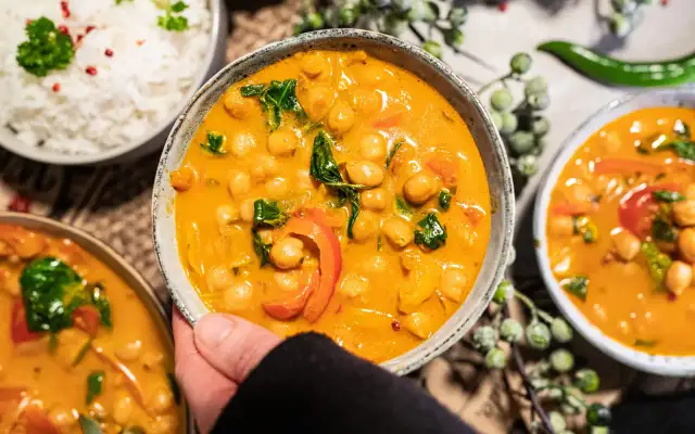 Ein köstliches veganes Curry mit Kichererbsen, Paprika und Spinat in cremiger Sauce, serviert mit Reis.