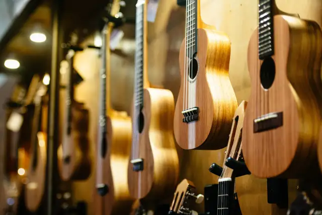 Rząd drewnianych ukulele wiszących na ścianie, z bliska.