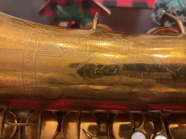 Złoty saksofon C.G. Conn z wygrawerowanym napisem i ornamentami.