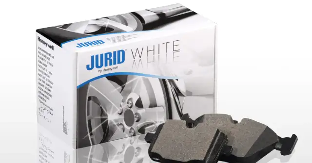 Dwa klocki hamulcowe Jurid White, wykonane z materiałów ceramicznych, leżą obok pudełka z tymi samymi klockami.