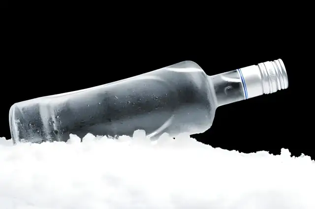 Szklana butelka z wódką leży w lodzie, budząc pytanie: czy wódka zamarznie?