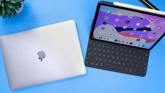 Geschlossenes MacBook neben einem geöffneten iPad Pro mit Tastatur und Apple Pencil.