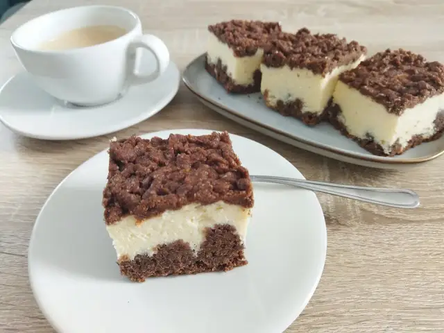 Sernik królewski stary przepis. Puszysty sernik z czekoladową kruszonką i kawą na drewnianym blacie.