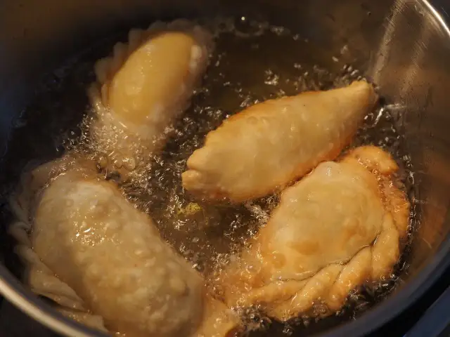 Empanadas de queso dorándose en aceite burbujeante. El aroma tentador llena la cocina.