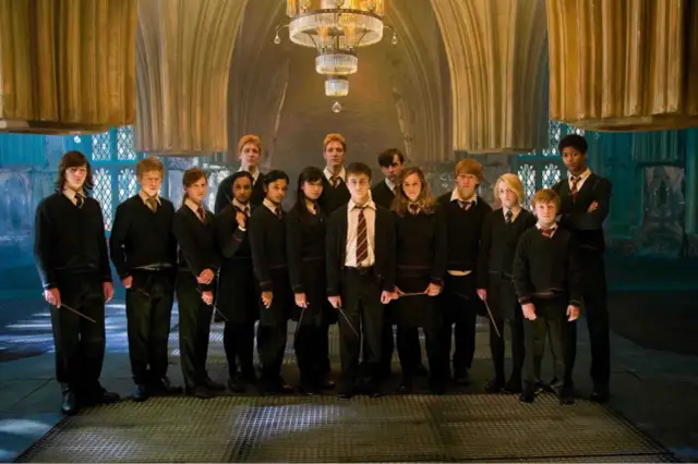 Grupa uczniów z domu Hufflepuff, w tym Harry Potter, stoi w eleganckiej sali.