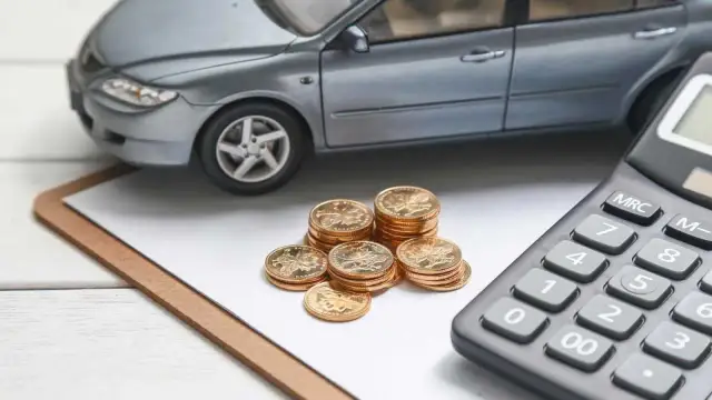 Model samochodu, stos monet i kalkulator. Obliczenia finansowe dla leasingu powyżej 150 tys. zł.