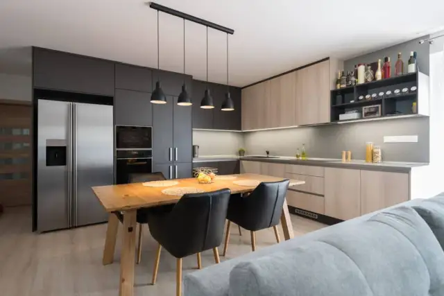 Moderna cocina abierta con isla de comedor, electrodomésticos integrados y estanterías para vinos.