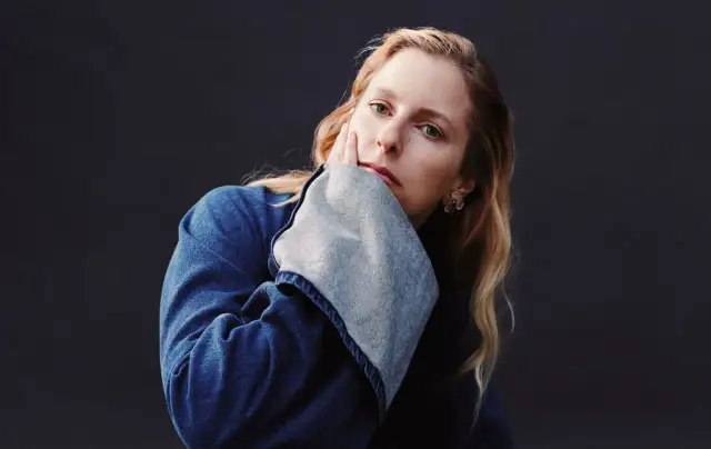 Susanne Sundfør w dżinsowej kurtce, z dłonią na policzku, jakby inspirowana utworem "Blómi".
