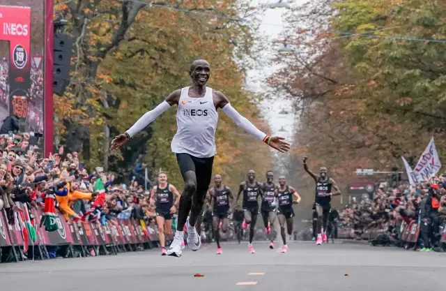 Eliud Kipchoge przekracza linię mety, ustanawiając nowy maraton rekord świata. Tłumy wiwatują, widząc historyczny bieg.
