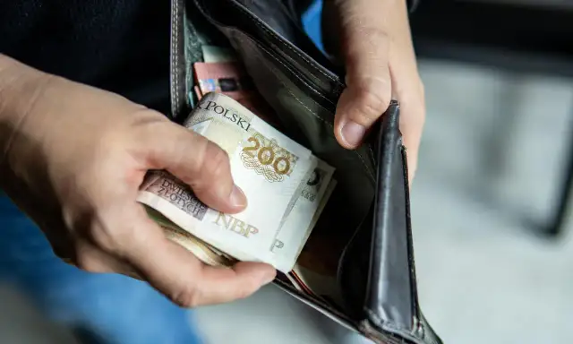 Ręce wkładają polskie banknoty do portfela. Czy to wystarczy na pensję minimalną 2026?