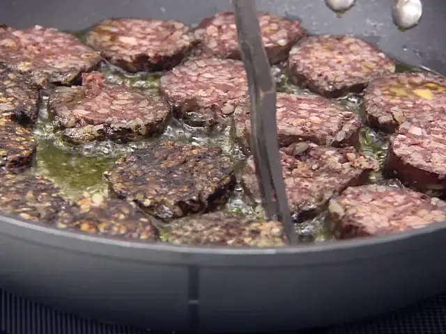 Rodajas de morcilla de Burgos dorándose en sartén con aceite burbujeante. Perfectas para tus recetas.