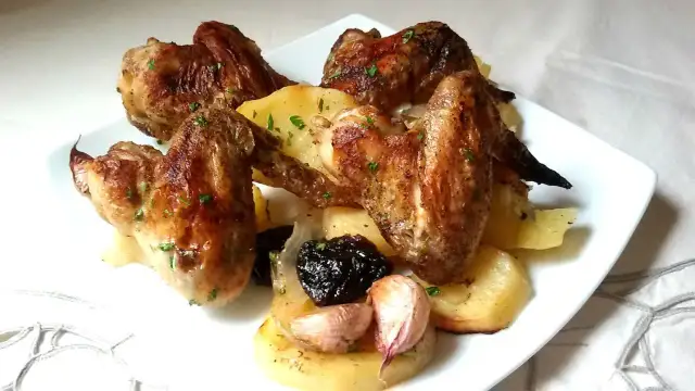 Alitas al horno con patatas, ajo y ciruelas pasas. Un plato casero y delicioso.