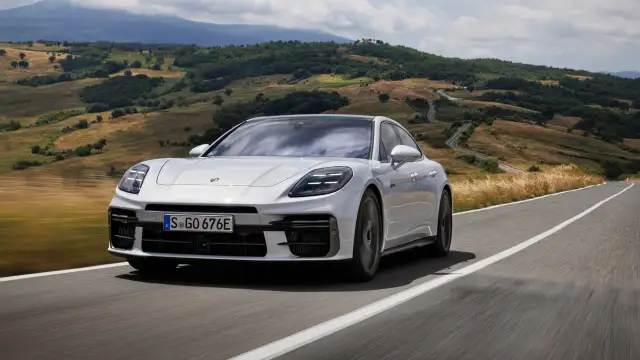 Białe Porsche Panamera GTS sunie po krętej drodze wśród malowniczych wzgórz Toskanii.