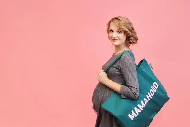 Przyszła mama z torbą "Mamahood" gotowa do szpitala. Sprawdź, co zabrać do szpitala, by niczego nie zapomnieć.