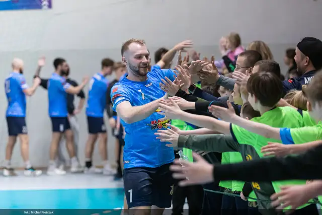 Gracz MKS Wieluń w niebieskiej koszulce z numerem 1 daje "piątki" młodym kibicom.