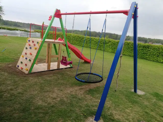 Plac zabaw z wspinaczką, zjeżdżalnią, huśtawkami i okrągłą huśtawką.