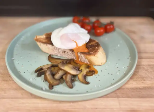 Un huevo poche perfecto sobre tostada con champiñones y tomates. ¡Así se hacen huevos poche deliciosos!