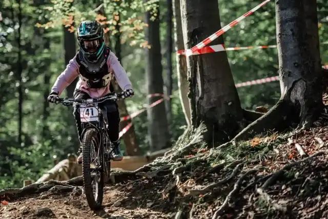 Rowerzystka w kasku z numerem 41 zjeżdża po leśnej ścieżce. To świetne **trasy rowerowe Śląsk** dla miłośników adrenaliny.