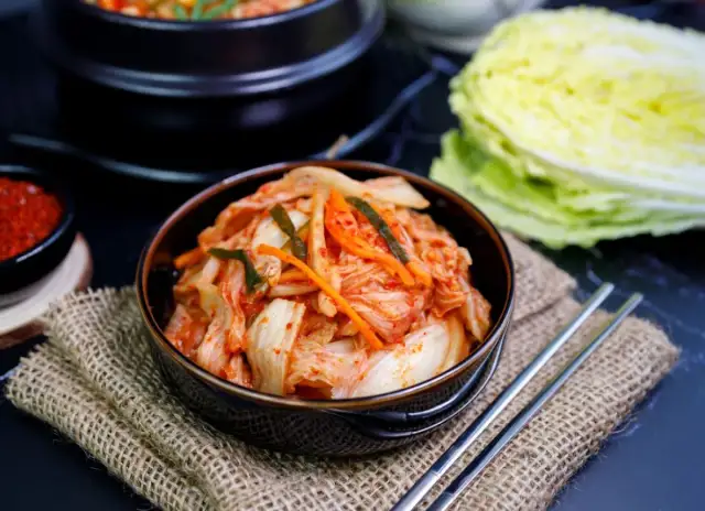 Miseczka z kimchi, obok pałeczki i kapusta pekińska.