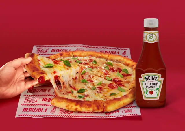 Ciepła pizza z ciągnącym serem i bazylią, obok butelka łagodnego ketchupu Heinz – idealny duet do każdego kęsa.