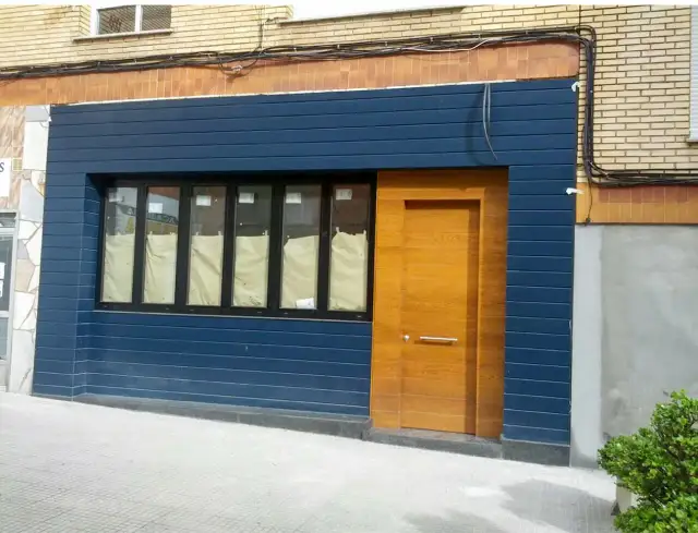 Fachadas de locales convertidos en viviendas, con puerta de madera y ventanas cubiertas.