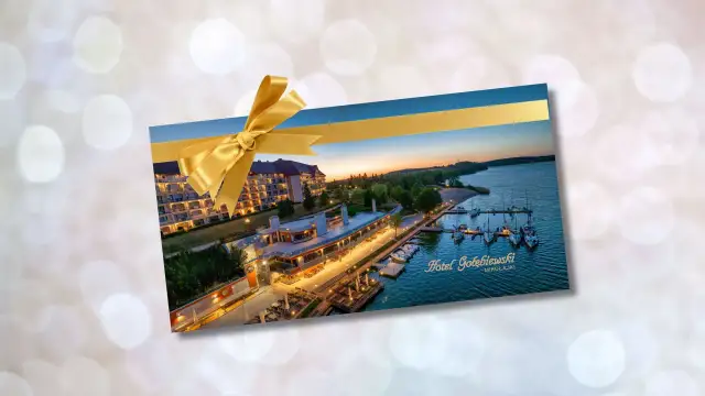 Złota karta Gołębiewski jak otrzymać? Voucher na pobyt w Hotelu Gołębiewski Mikołajki, ozdobiony złotą wstążką.