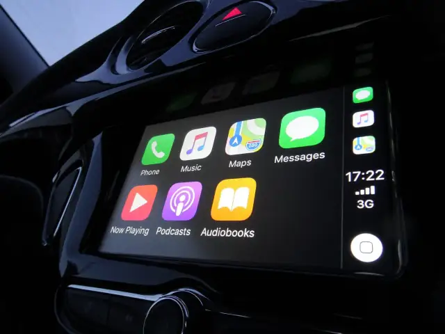 Ekran samochodu z ikonami Apple CarPlay: Telefon, Muzyka, Mapy, Wiadomości, Teraz odtwarzane, Podcasty, Audiobooki.