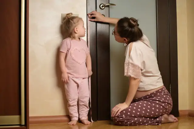 Mama mierzy wzrost dziecka przy drzwiach, sprawdzając, co na wzrost u dziecka.