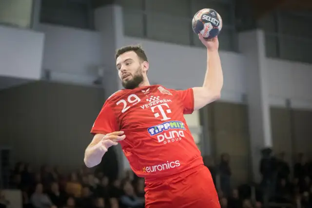 Piłkarz ręczny Nedim Remili w czerwonej koszulce z numerem 29, z piłką w dłoni, gotowy do rzutu.