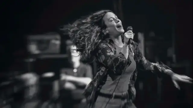 Energetyczny alanis morissette koncert, wokalistka śpiewa z pasją, włosy rozwiane w locie.