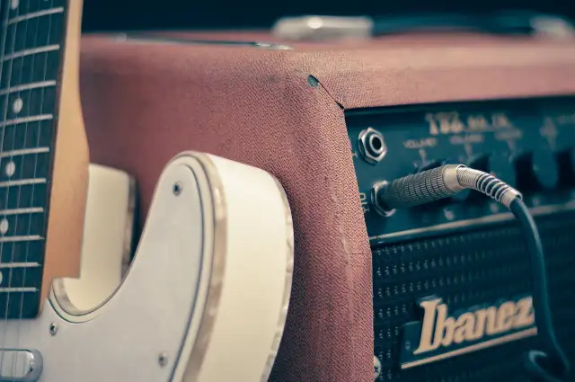 Biała gitara elektryczna podłączona do wzmacniacza Ibanez. Idealny zestaw do nauki gry na gitarze elektrycznej.