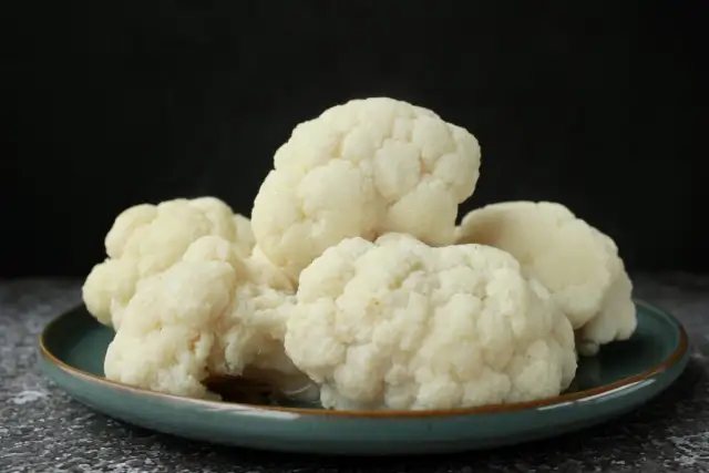 Montón de coliflor cocida en un plato verde, lista para tu receta.