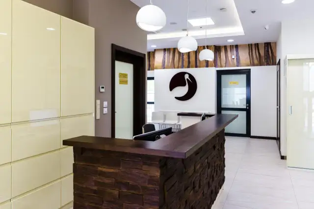 Nowoczesna recepcja kliniki Bocian Katowice. Elegancka lada, logo bociana i stylowe oświetlenie tworzą przyjazną atmosferę.