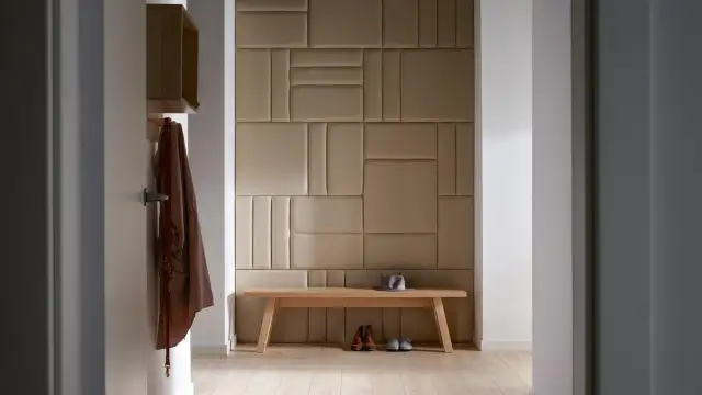 Nowoczesny przedpokój inspiracje ściany: tapicerowane panele tworzą geometryczną mozaikę, drewniana ławka z butami i kapeluszem.