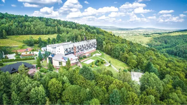 Hotel w otoczeniu zielonych lasów Gór Świętokrzyskich, z widokiem na dolinę.