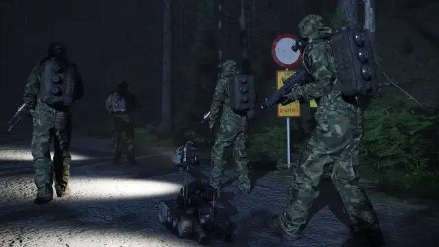 Żołnierze w kamuflażu i robot zwiadowczy na nocnej drodze leśnej.