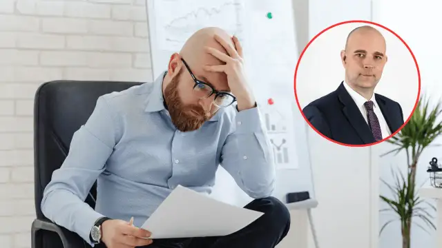 Zmartwiony mężczyzna analizuje dokumenty, podczas gdy w tle widać portret biznesmena. Obraz symbolizuje analizę przyczyn bezrobocia w Polsce.