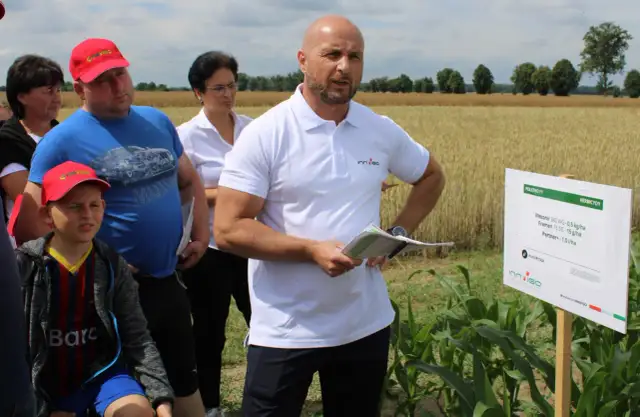 Grupa ludzi na polu kukurydzy, gdzie prezentowane są środki ochrony roślin, w tym metkonazol.