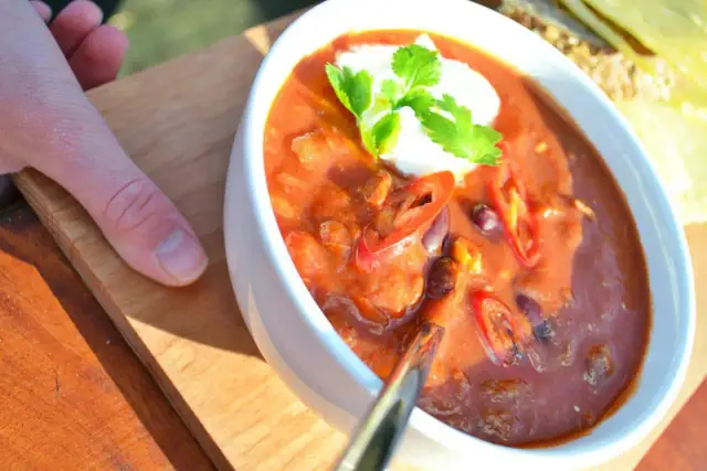 Aksamitna zupa meksykańska z pulpecikami, ozdobiona kleksem śmietany i świeżą kolendrą, z plasterkami chili.