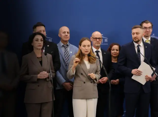 Grupa osób na tle niebieskiej ściany. Kobieta przemawia do mikrofonu, gestykulując. W tle inni mężczyźni i kobiety. Czym Polska 2050 różni się historycznie od nowoczesnej?