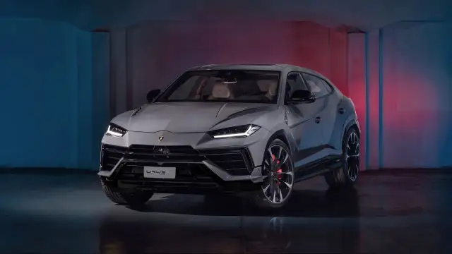 Szary Lamborghini Urus S z czerwonymi zaciskami hamulcowymi stoi w studiu z niebieskim i czerwonym oświetleniem.