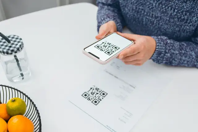 Une personne scanne un QR code sur un document avec son téléphone, peut-être pour activer une carte eSIM Bouygues.