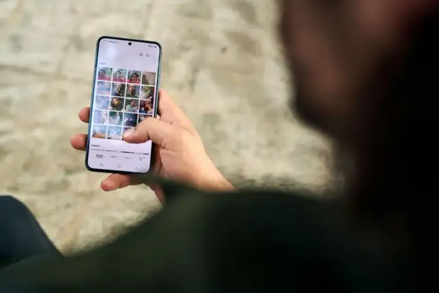 Osoba przegląda zdjęcia na telefonie, zastanawiając się, jak usunąć aplikacje z telefonu, by zwolnić miejsce.