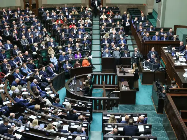 Posłowie w sali sejmowej, dyskutują o tym, ile wynosi dieta poselska.