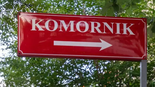 Czerwony znak drogowy z napisem "KOMORNIK" i białą strzałką w prawo. Może symbolizować drogę do komornika, gdy umowa zlecenie jest zagrożona.